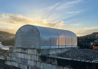 Freestanding covered storage structure with enclosed gable end, providing protected storage for materials and equipment.