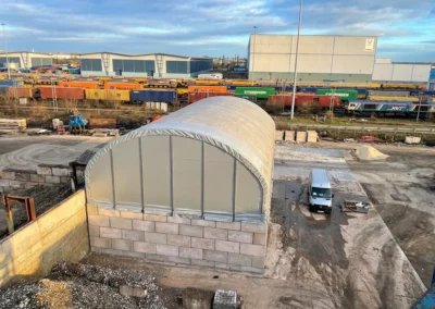 A TUFFShel Max large span industrial shelter installed on block walls, providing high-capacity covered storage on a working site.